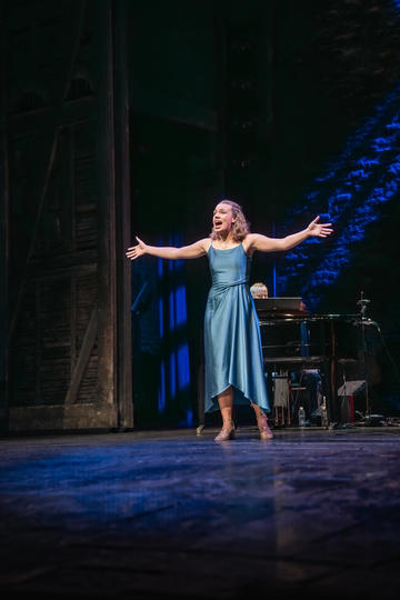Rosie Sutton singing with arms outstretched