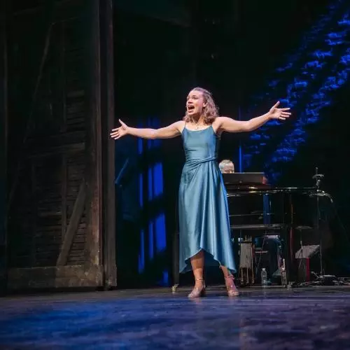 Rosie Sutton singing with arms outstretched